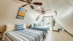 Een slaapkamer met twee bedden, houten vloeren, plafondventilatoren en een raam.