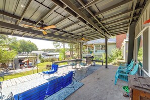Eine Terrasse im Freien mit blauen Stühlen, einem Tisch und einem Deckenventilator.
