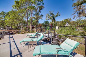 Un espace patio aménagé avec des chaises longues et une table, entouré d’arbres et d’un bâtiment.