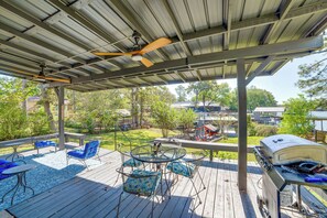 Eine überdachte Terrasse im Freien mit Grill, Sitzgelegenheit und Blick auf die Nachbarschaft.
