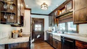 A kitchen with wooden cabinets, a dishwasher, a sink, and a window with blinds.