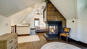 A cozy attic bedroom with a fireplace, a bed, and a wooden dresser.