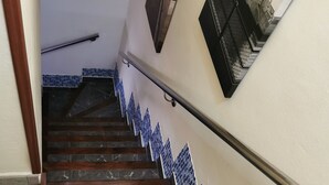A staircase with a handrail, tiled steps, and a wall-mounted picture frame.