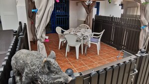 A patio area with a table and chairs, a decorative animal statue, and a gated entrance.