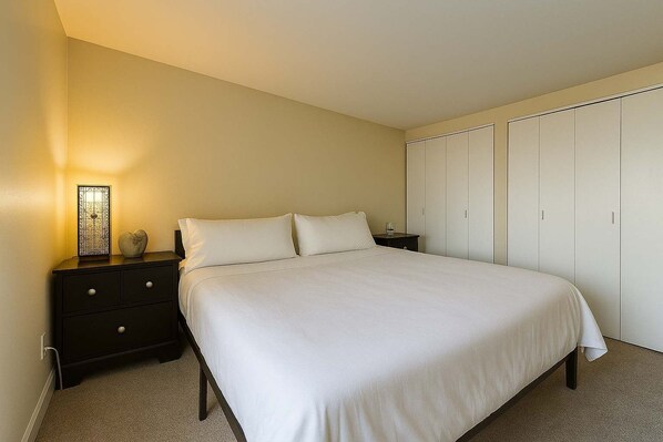A bedroom with a bed, nightstands, a dresser, and a wardrobe.