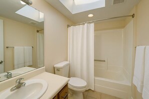 A bathroom with a sink, toilet, shower, and a skylight. - Pet-Friendly Soulard Townhouse · 2BR/2BA · Parking + Rooftop Deck (St. Louis)