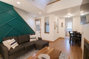 Ein modernes Wohnzimmer mit einer Eckcouch, einem Couchtisch und einem Essbereich mit Tisch und Stühlen.