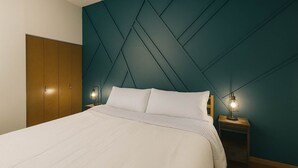 Ein Schlafzimmer mit einem Bett, zwei Nachttischen mit Lampen, einem Kleiderschrank und einer Türkis-farbenen Akzentwand.