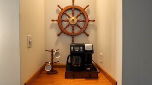 Ein Flur mit einer hölzernen Kaffeemaschine, einer Kaffeekanne und einem Schiffswellenrad an der Wand.