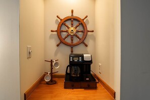 A hallway with a wooden coffee maker, a coffee pot, and a ship's wheel on the wall. - Soulard River-View Loft - 2 King BR - Parking (St. Louis)