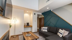 Ein modernes Wohnzimmer mit einer Couch, einem Couchtisch und einem an der Wand montierten Fernseher.