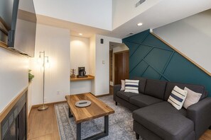 A modern living room with a sofa, coffee table, and a wall-mounted TV. - Soulard River-View Loft - 2 King BR - Parking (St. Louis)