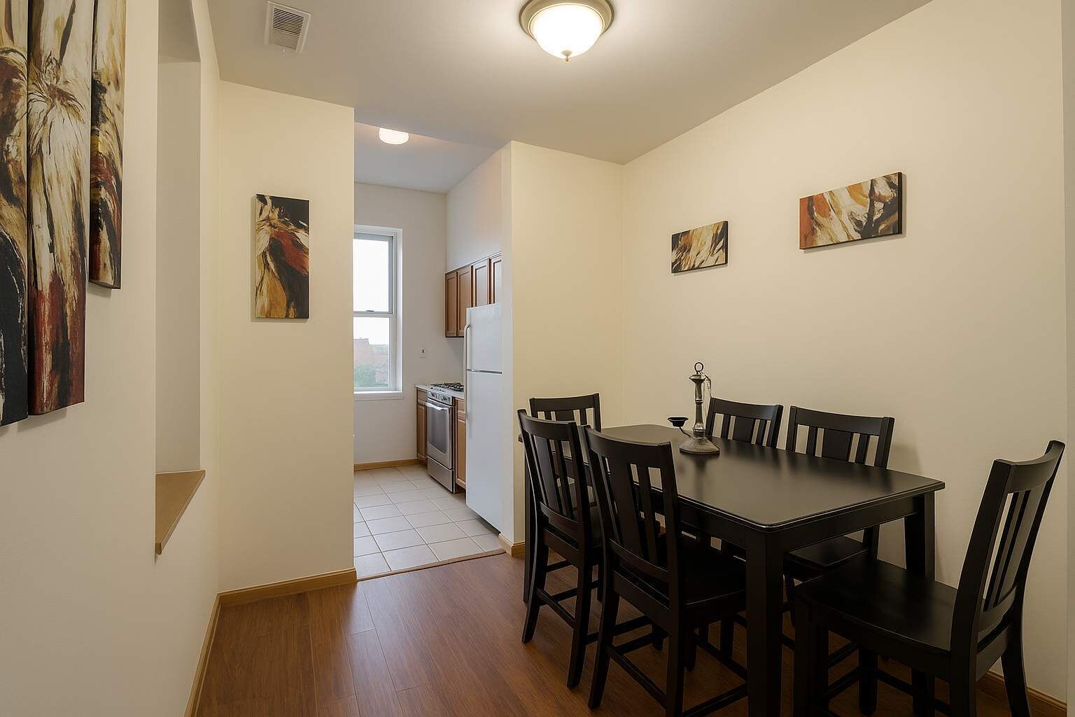 Een eetgedeelte met een tafel en stoelen, een keuken op de achtergrond en abstracte kunst aan de muren.