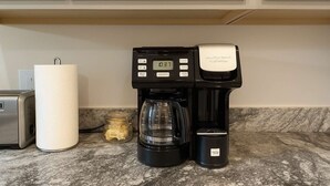 Une machine à café, un bocal et un rouleau d’essuie-tout sur un plan de travail de cuisine.
