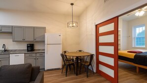 Un espace de vie compact comprenant un coin cuisine, un coin repas, un canapé et un lit.