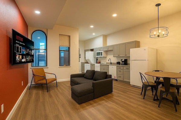 Open-plan living space: sectional, kitchen, and dining nook under a pendant light.