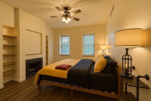 Une chambre à coucher avec un lit, un ventilateur de plafond, une lampe et une cheminée.