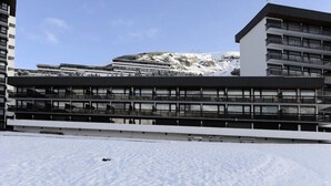 Un edificio moderno a più piani con tetto piatto e ampie finestre, immerso nella neve.