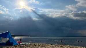 Ein Strand mit einem Zelt und Personen im Wasser.