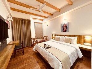 A hotel room with a large bed, wooden floor, a desk, and a chair. - Yaato Retreat (Manali)