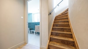 A wooden staircase with a handrail, leading to a room with a bench and a table. - Holiday Home in Middelkerke Near Beach (Middelkerke)