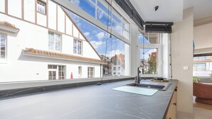 A modern kitchen with a large window, a black countertop, and a sink. - Holiday Home in Middelkerke Near Beach (Middelkerke)