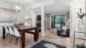 Ein moderner Essbereich mit einem Holztisch und Stühlen, einem großen abstrakten Gemälde und Blick ins Freie durch ein großes Fenster.