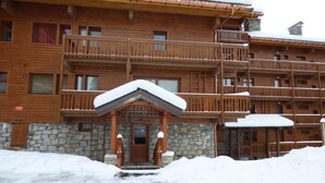 A wooden building with multiple balconies and a stone entrance. - Apartment in Meribel With Mountain Views (Les Allues)