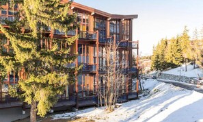 A multi-story building with balconies, surrounded by snow and trees. - Quiet Mezzanine Duplex for 6 People (Bourg-Saint-Maurice)