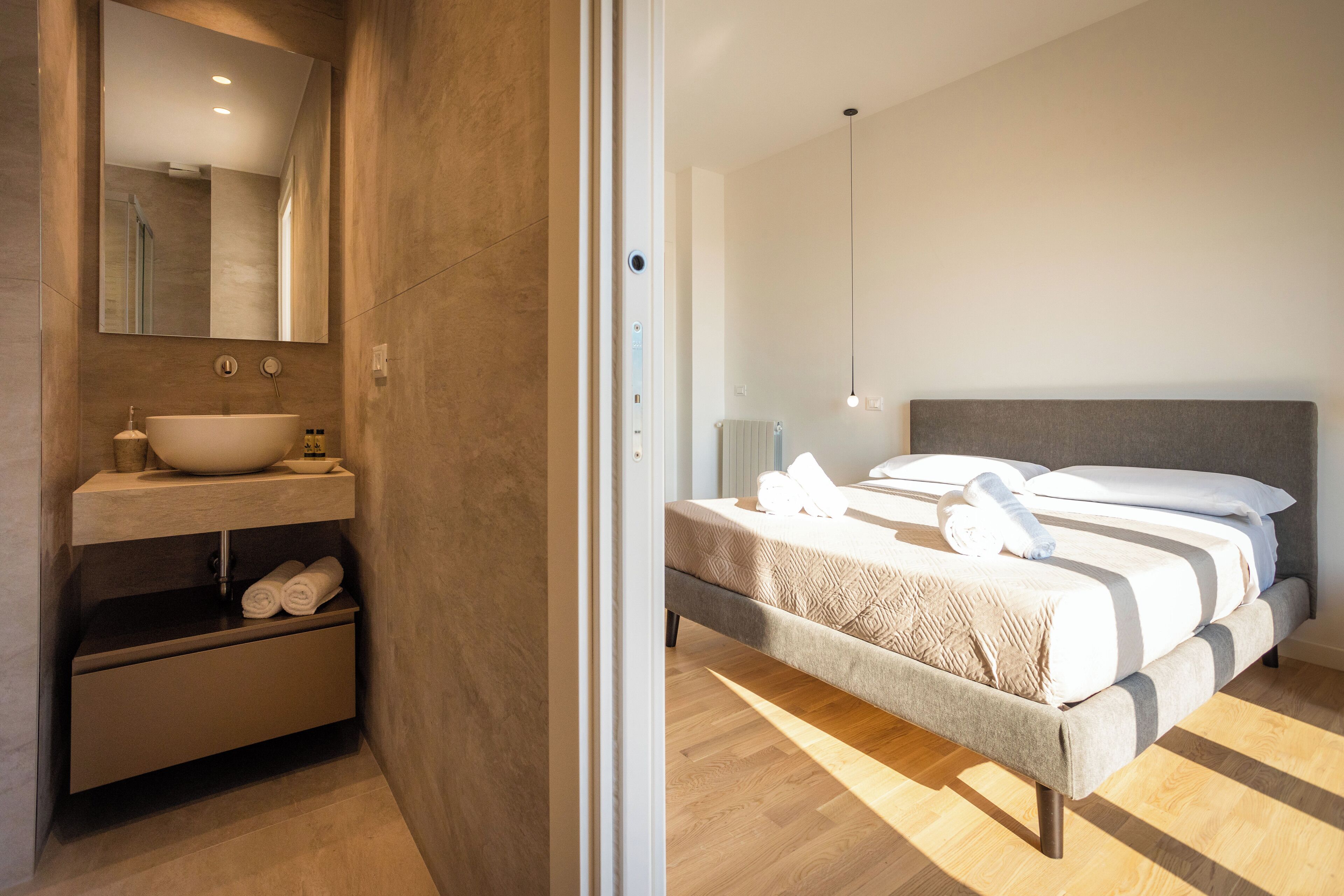 A modern bedroom with a large bed, a bedside table, and a built-in sink with a mirror.