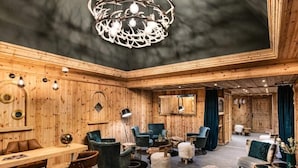 A cozy, wooden-furnished room with a dining area, two sofas, and a chandelier. - 5 Rooms, Sleeps 8 (Les Belleville)
