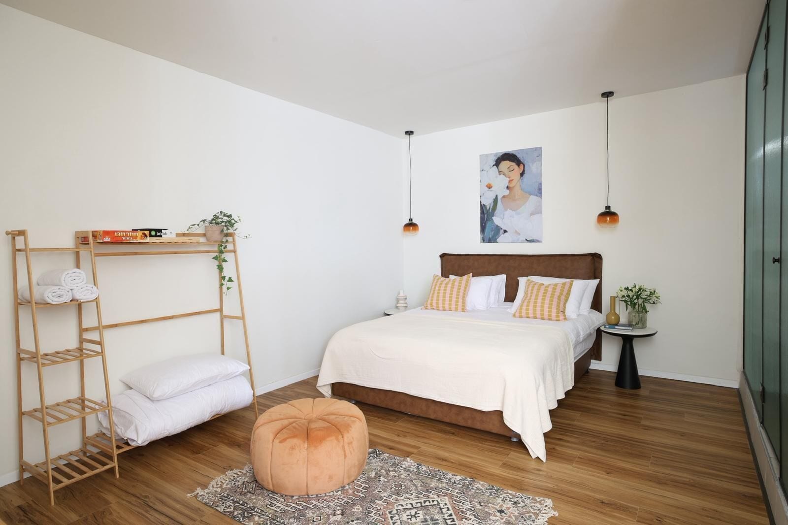 A bedroom with a wooden bunk bed, a bedside table with a vase, a hanging light, and a painting on the wall.