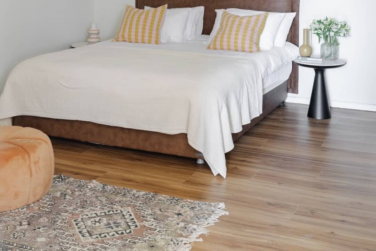 Ein Schlafzimmer mit einem hölzernen Kopfteil, einer weißen Bettdecke und zwei Nachttischlampen.