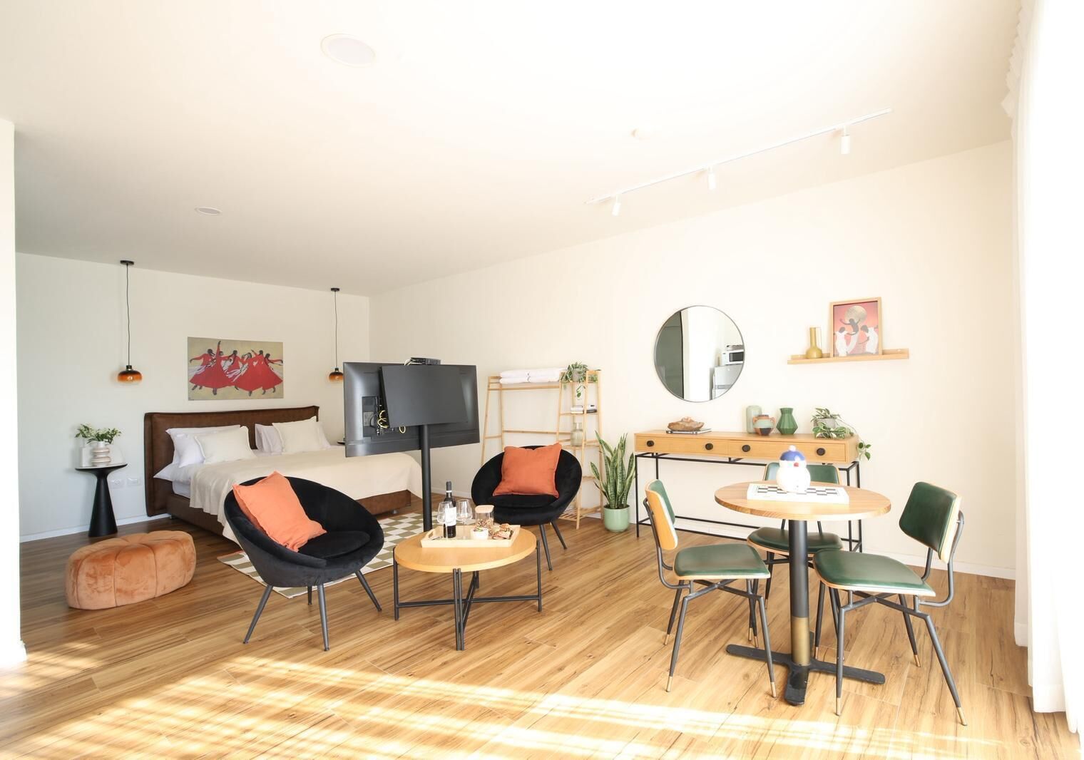 A modern living room with a bed, two armchairs, a coffee table, and a dining area with chairs and a table.