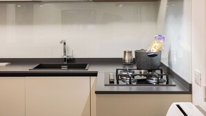 A modern kitchen with a black countertop, a stainless steel sink, and a stove. - Luxury Apartment Cefalù Giglio (Cefalù)