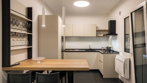 A compact kitchen with a wooden table, two chairs, a wine rack, and a built-in oven. - Luxury Apartment Cefalù Giglio (Cefalù)