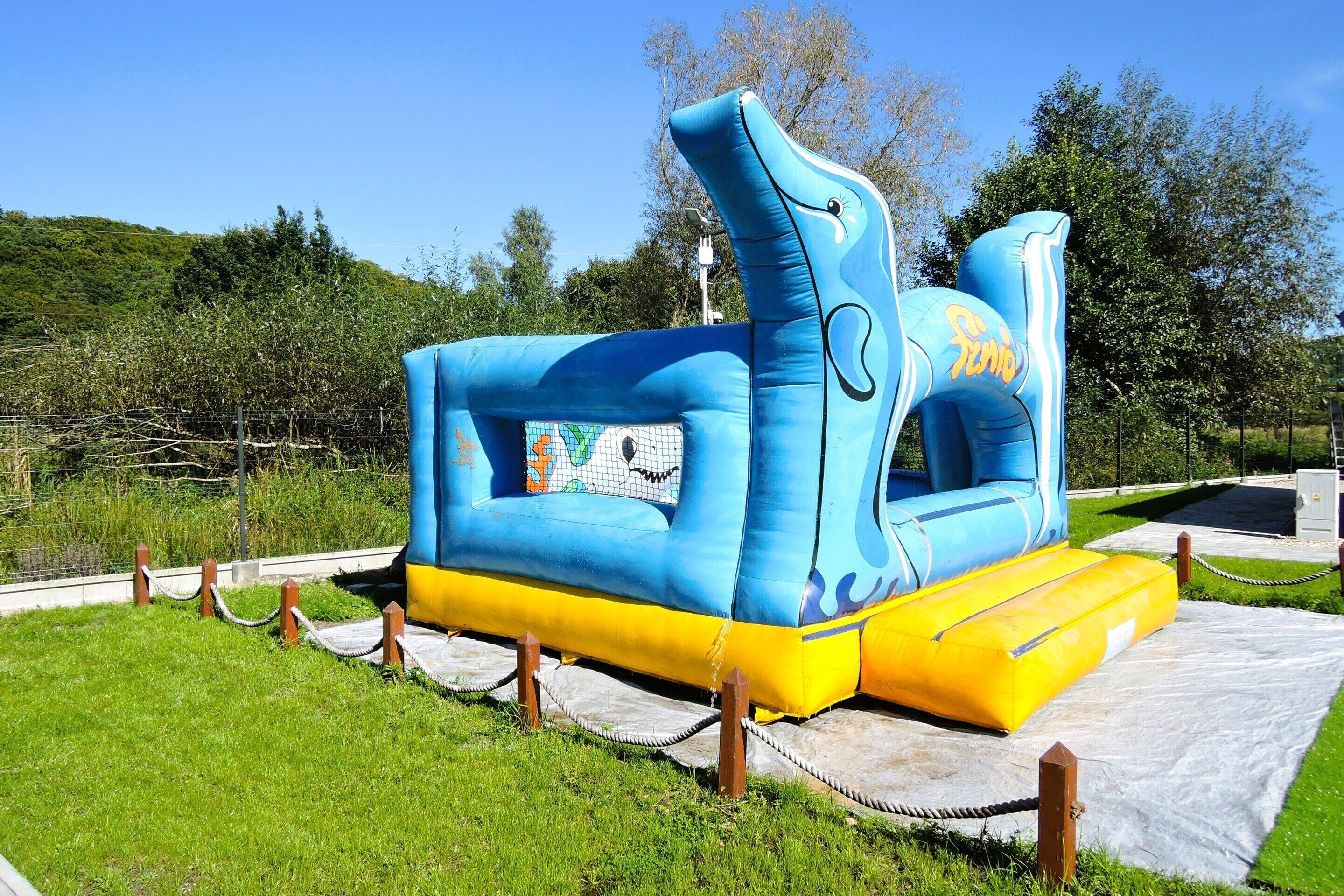 A blue and yellow inflatable structure with the word "Sunda" on it, surrounded by a grassy area and trees.