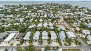 An aerial view of a coastal residential area with houses, roads, and a beach. - Chilli Fish 4 Bedroom Home (Anna Maria)