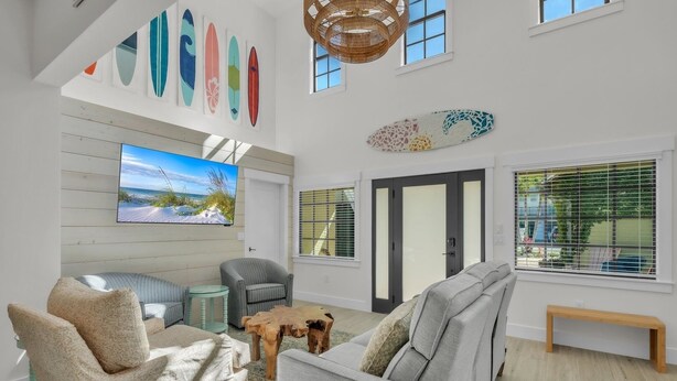 A spacious living room with a large TV, comfortable seating, and a view of the outdoors. - Chilli Fish 4 Bedroom Home (Anna Maria)