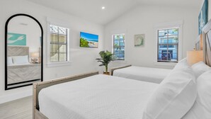 A bedroom with two beds, a large mirror, and artwork on the walls. - Chilli Fish 4 Bedroom Home (Anna Maria)