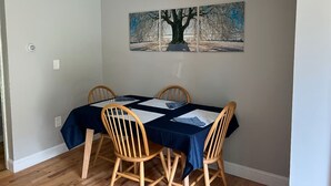 Ein Essbereich mit einem für vier Personen gedeckten Tisch, einem Gemälde an der Wand und einem Holzboden.