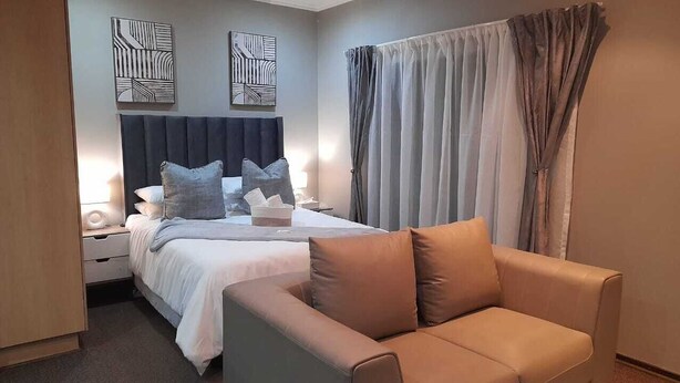 Ein modernes Hotelzimmer mit einem Bett, einer Couch und zwei abstrakten Wandbildern.