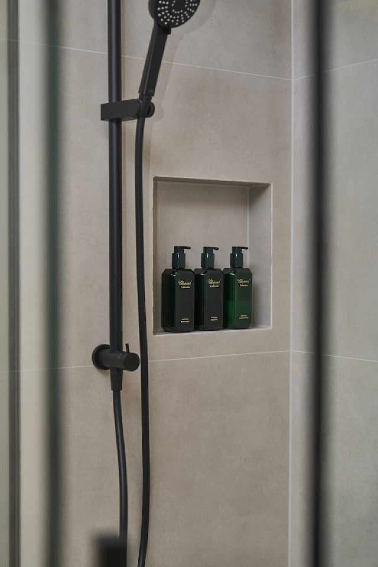 Une douche équipée d’une étagère intégrée où l’on peut ranger trois bouteilles de shampoing.