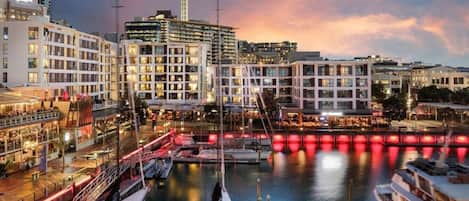 A waterfront hotel with multiple floors, a prominent tower, and a dock with boats.