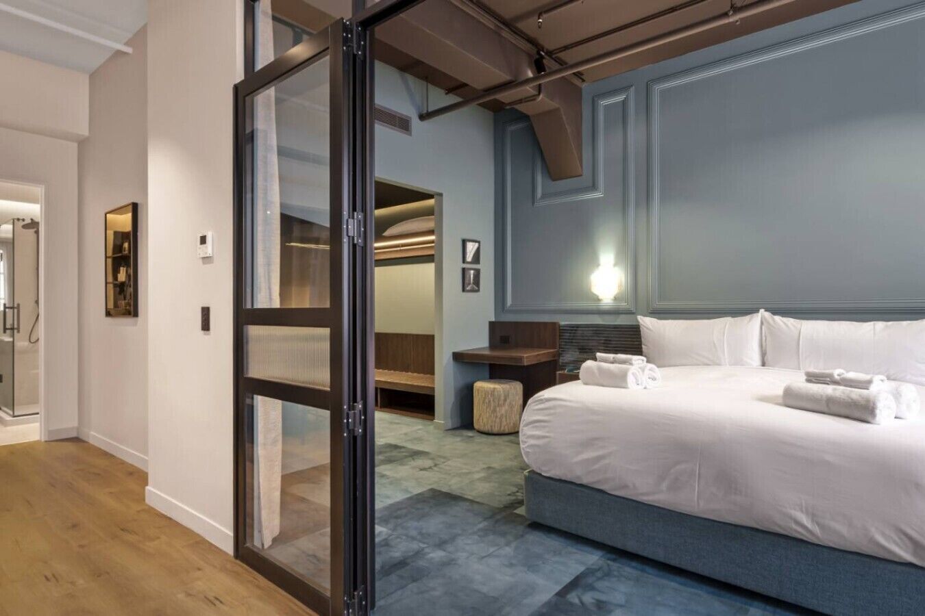 Ein Hotelzimmer mit Bett, Nachttisch, Lampe und einer Schiebetür zu einem Badezimmer.