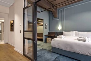 Een hotelkamer met een bed, een nachtkastje, een lamp en een schuifdeur naar een badkamer.