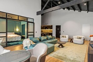 A modern interior with a bed, sofa, chairs, a dining table, and a kitchen area. - Serene Heritage Penthouse in the Heart of Auckland (Auckland)