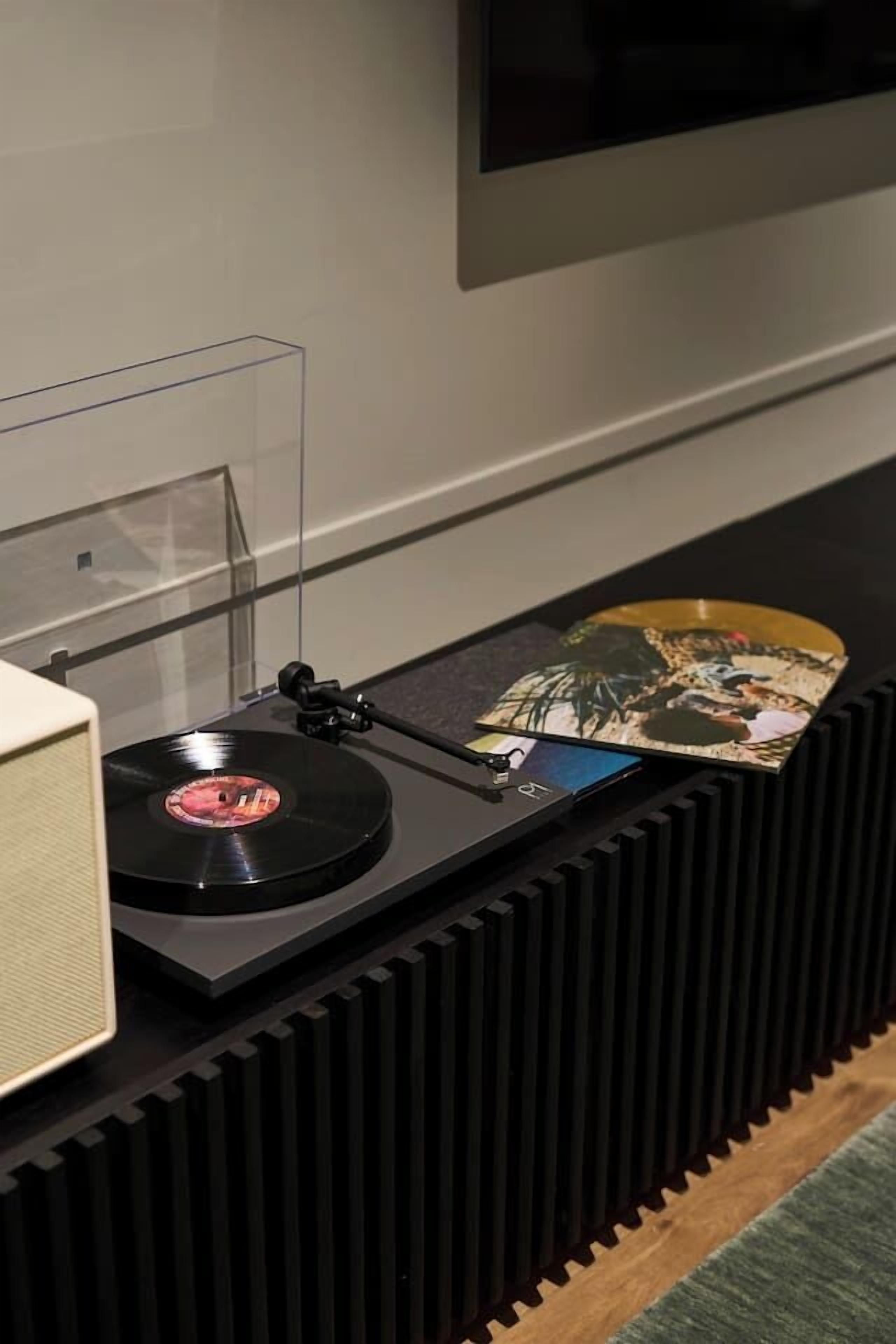 Une platine vinyle avec un disque en vinyle et un CD posés sur une surface noire.
