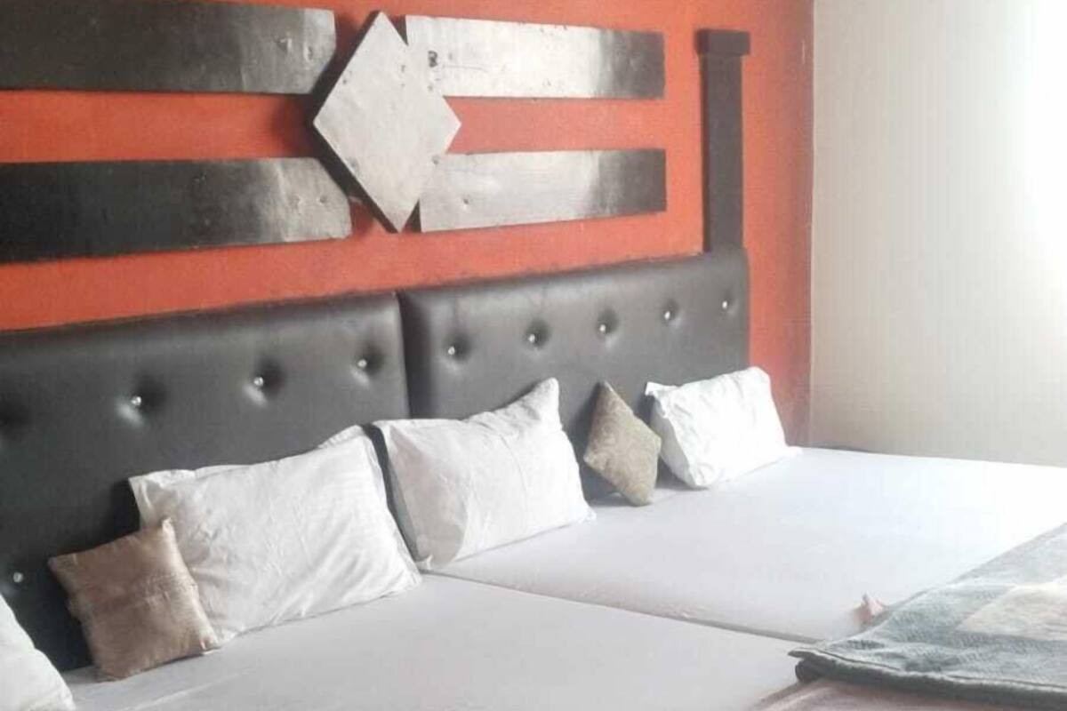 A hotel room with a large bed, a wooden headboard, and a red accent wall.