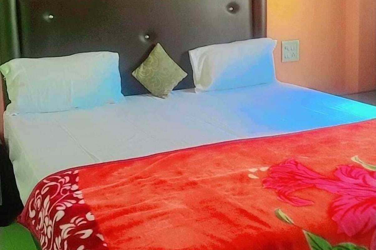 A bed with a red floral bedspread, two pillows, and a headboard.